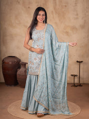 Model wearing a sage green georgette sharara suit with a sleeveless floral-embroidered kurta, flared trousers, and a matching dupatta with decorative trim.